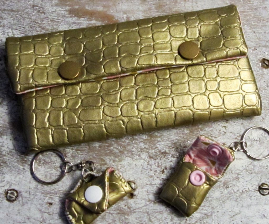 Pochette en simili cuir or, doublée en tissu coton rose et or ; porte-clés en forme de pochettes miniatures en simili cuir or, doublées de tissu coton